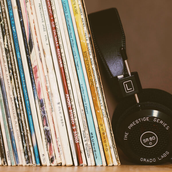Music albums are lined up on a shelf bookended by a headset