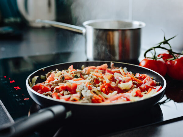 Frying pan on induction cooker preparing spaghetti bolognese sauce for dinner