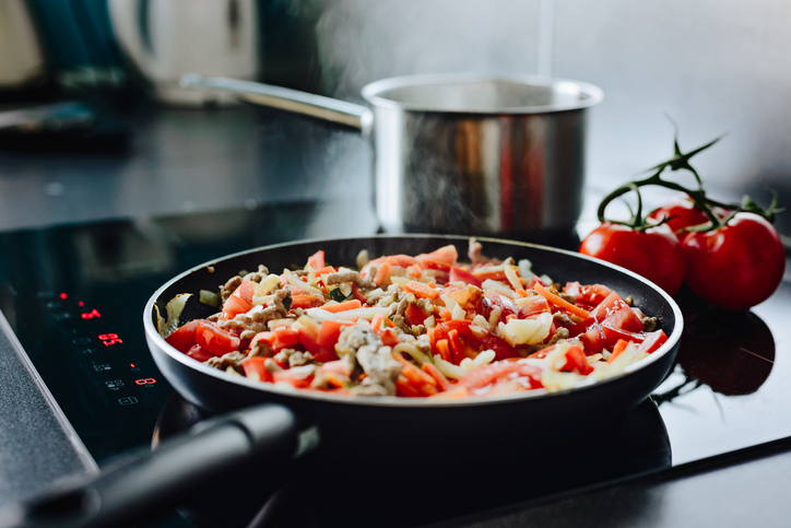 Frying pan on induction cooker preparing spaghetti bolognese sauce for dinner