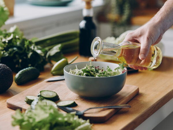 Olive oil being poured over a salad in a small bowl