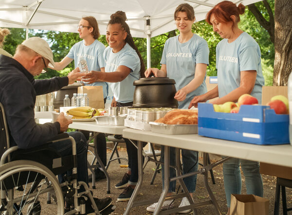 Homeless older adult in a wheelchair receiving a meal from a food line