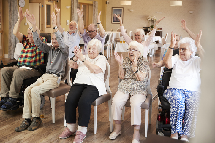 Group of older adults doing seated exercises.