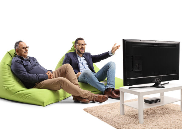 young man and older man sitting on bean bag chairs in front of the tv