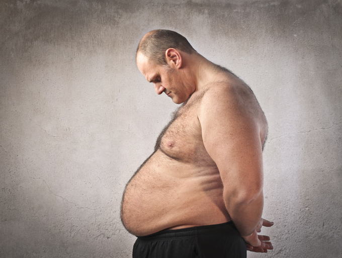 A man is shown in profile looking down at his large belly