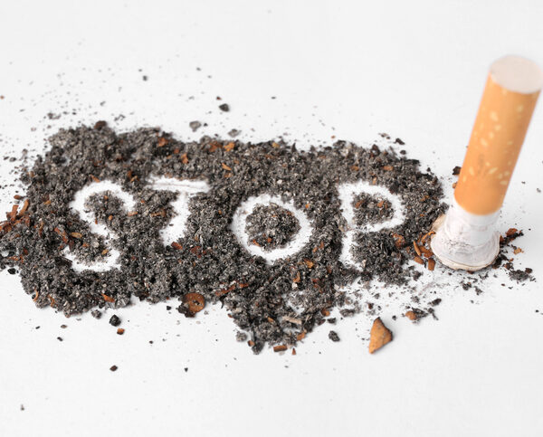 Cigarette ash with the word STOP scrawled in the middle and a cigarette stub on the right side.