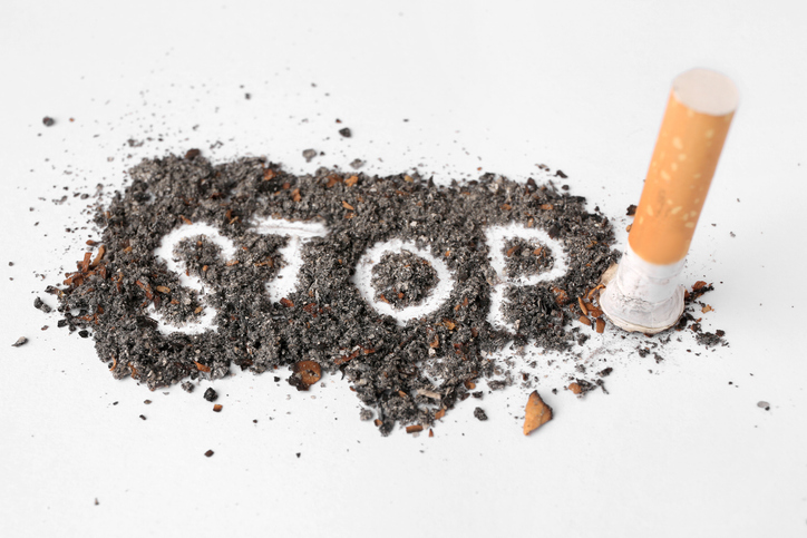 Cigarette ash with the word STOP scrawled in the middle and a cigarette stub on the right side.