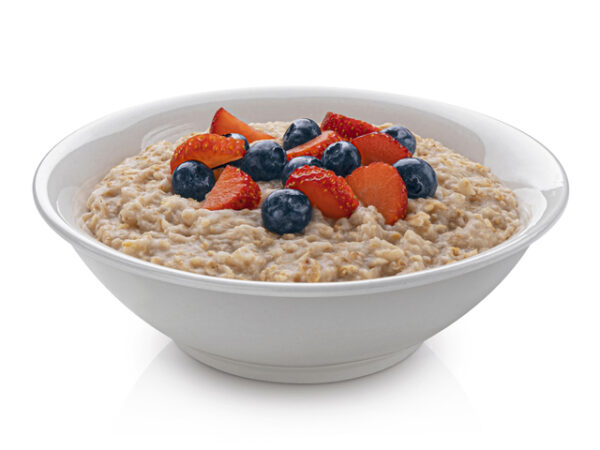 A bowl of oatmeal topped with a few blueberries and strawberries